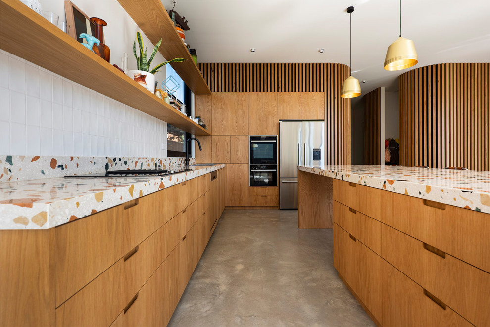Stilmix Küche mit Doppelwaschbecken, hellen Holzschränken, Arbeitsplatte aus Terrazzo, Küchenrückwand in Weiß, Rückwand aus Keramikfliesen, Betonboden, grauem Boden und bunter Arbeitsplatte in Melbourne