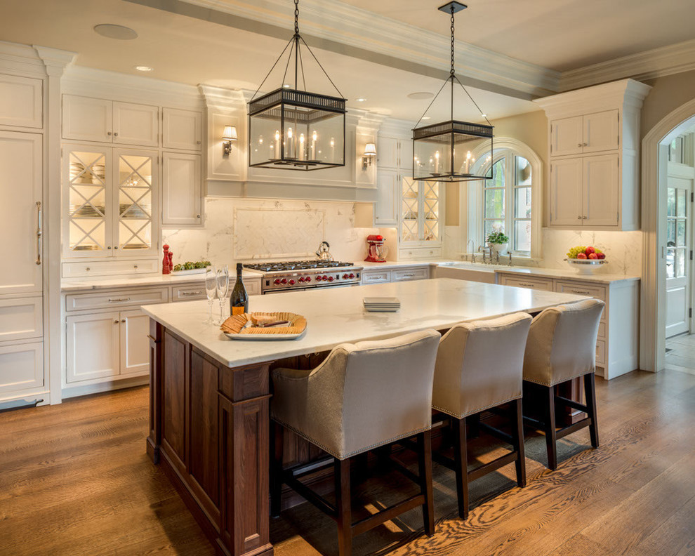 Inspiration for a large traditional l-shaped eat-in kitchen in Philadelphia with a farmhouse sink, glass-front cabinets, white cabinets, marble benchtops, white splashback, stone slab splashback, stainless steel appliances and medium hardwood floors.