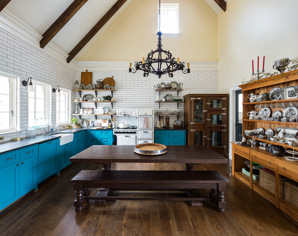 Inspiration for a country l-shaped eat-in kitchen in Atlanta with a farmhouse sink, shaker cabinets, turquoise cabinets, white splashback, subway tile splashback, white appliances, dark hardwood floors, brown floor and black benchtop.