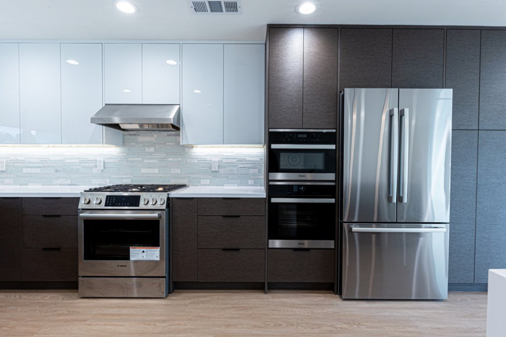 Zweizeilige Moderne Küche mit Unterbauwaschbecken, Rückwand aus Glasfliesen, Küchengeräten aus Edelstahl, hellem Holzboden, Kücheninsel, braunem Boden und weißer Arbeitsplatte in San Francisco