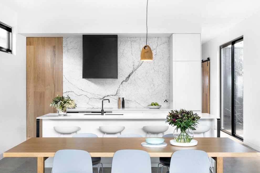 Design ideas for a contemporary eat-in kitchen in Melbourne with an undermount sink, flat-panel cabinets, white cabinets, white splashback, stone slab splashback, concrete floors and with island.