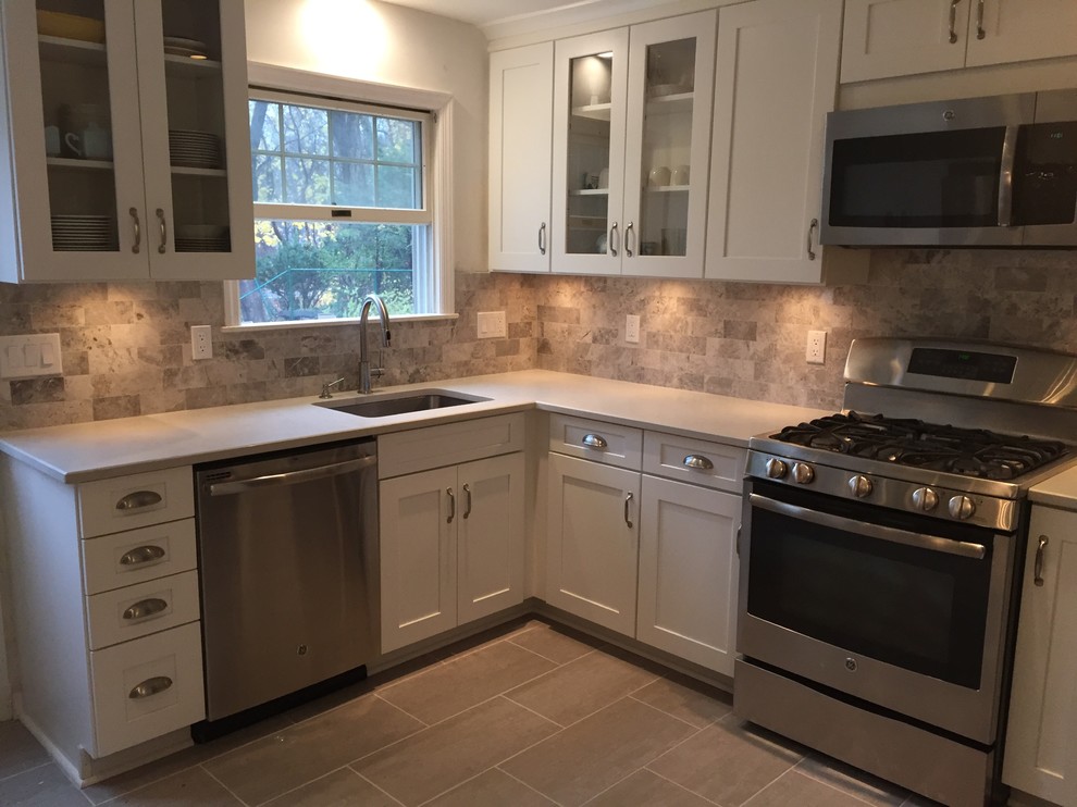 This is an example of a mid-sized transitional l-shaped eat-in kitchen in New York with an undermount sink, shaker cabinets, white cabinets, quartz benchtops, grey splashback, stone tile splashback, stainless steel appliances, porcelain floors and no island.