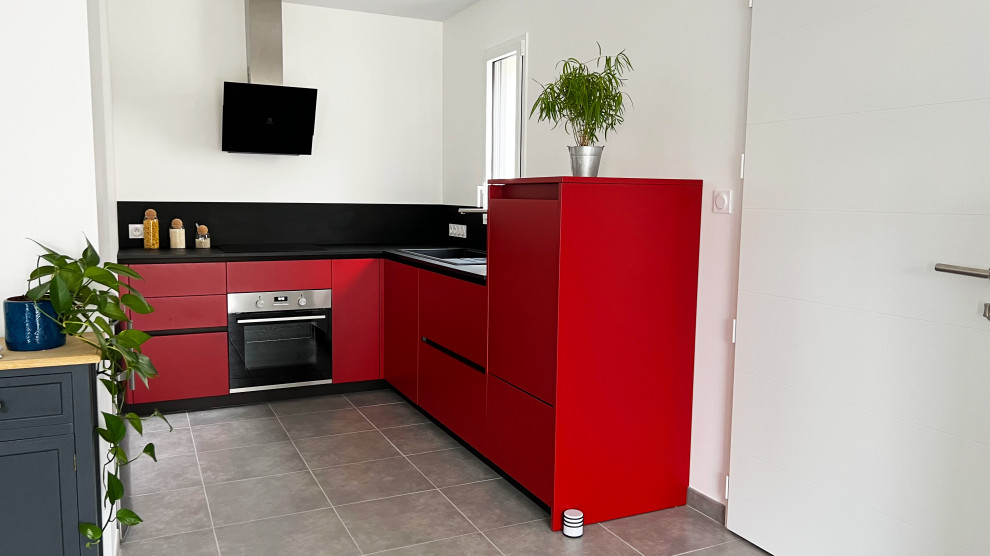 This is an example of a small contemporary l-shaped open plan kitchen in Nantes with an undermount sink, red cabinets, laminate benchtops, black splashback, panelled appliances, no island, grey floor and black benchtop.