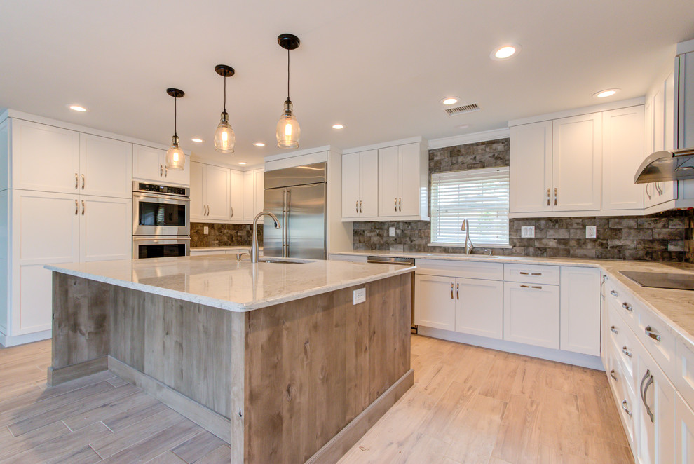 Inspiration for a large transitional u-shaped porcelain tile and brown floor enclosed kitchen remodel with an undermount sink, shaker cabinets, white cabinets, quartz countertops, brown backsplash, stainless steel appliances, an island and beige countertops