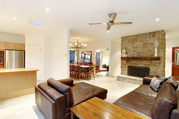 This is an example of a mid-sized beach style open concept family room in Melbourne with white walls, limestone floors, a standard fireplace, a stone fireplace surround and no tv.