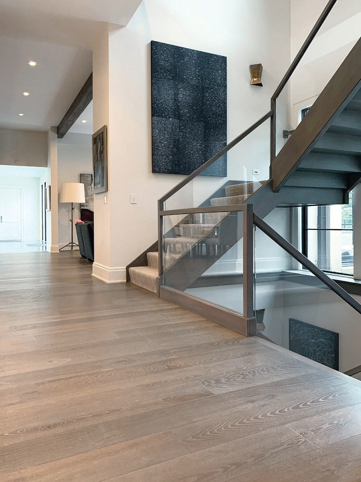 Cette image montre un grand escalier minimaliste en U avec des marches en moquette, des contremarches en moquette, un garde-corps en verre et éclairage.