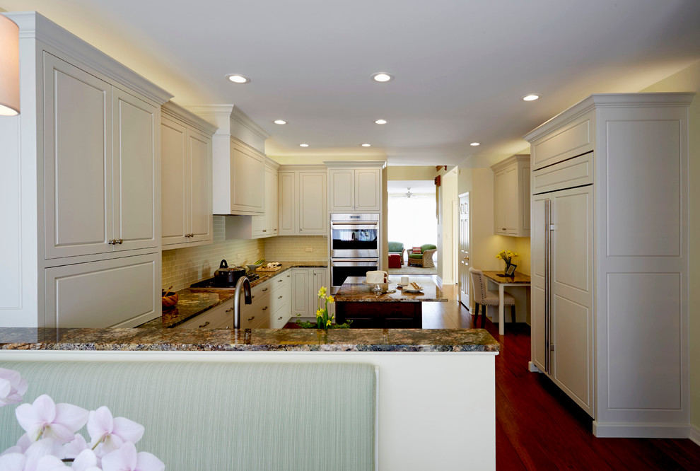 Enclosed kitchen - mid-sized transitional u-shaped medium tone wood floor enclosed kitchen idea in Chicago with a single-bowl sink, raised-panel cabinets, white cabinets, granite countertops, white backsplash, glass tile backsplash, stainless steel appliances and an island