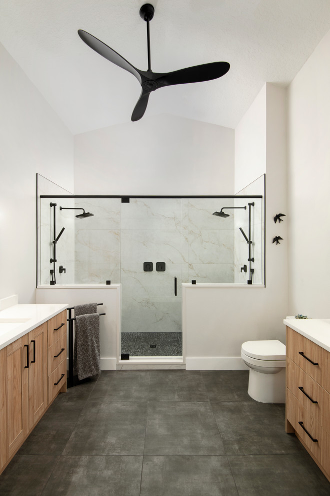 Пример оригинального дизайна: большая главная ванная комната в скандинавском стиле с плоскими фасадами, светлыми деревянными фасадами, двойным душем, унитазом-моноблоком, белой плиткой, керамогранитной плиткой, белыми стенами, полом из керамогранита, врезной раковиной, столешницей из искусственного кварца, серым полом, душем с распашными дверями, белой столешницей, нишей, тумбой под две раковины и сводчатым потолком
