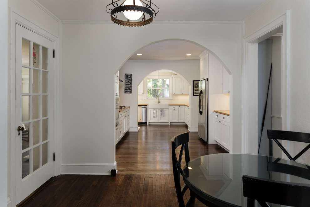 Example of a large transitional l-shaped dark wood floor eat-in kitchen design in Raleigh with shaker cabinets, white cabinets, stainless steel appliances, a farmhouse sink, beige backsplash, subway tile backsplash and no island