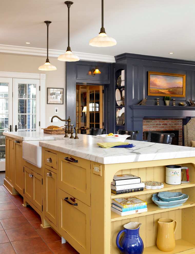 Large traditional open plan kitchen in New York with shaker cabinets, yellow cabinets, terra-cotta floors and with island.