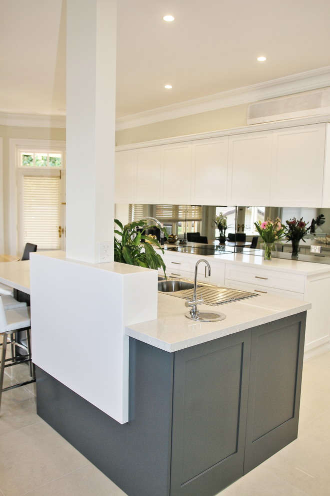 Inspiration for a large transitional l-shaped eat-in kitchen in Sydney with a drop-in sink, shaker cabinets, white cabinets, quartz benchtops, grey splashback, glass sheet splashback, stainless steel appliances, ceramic floors and with island.
