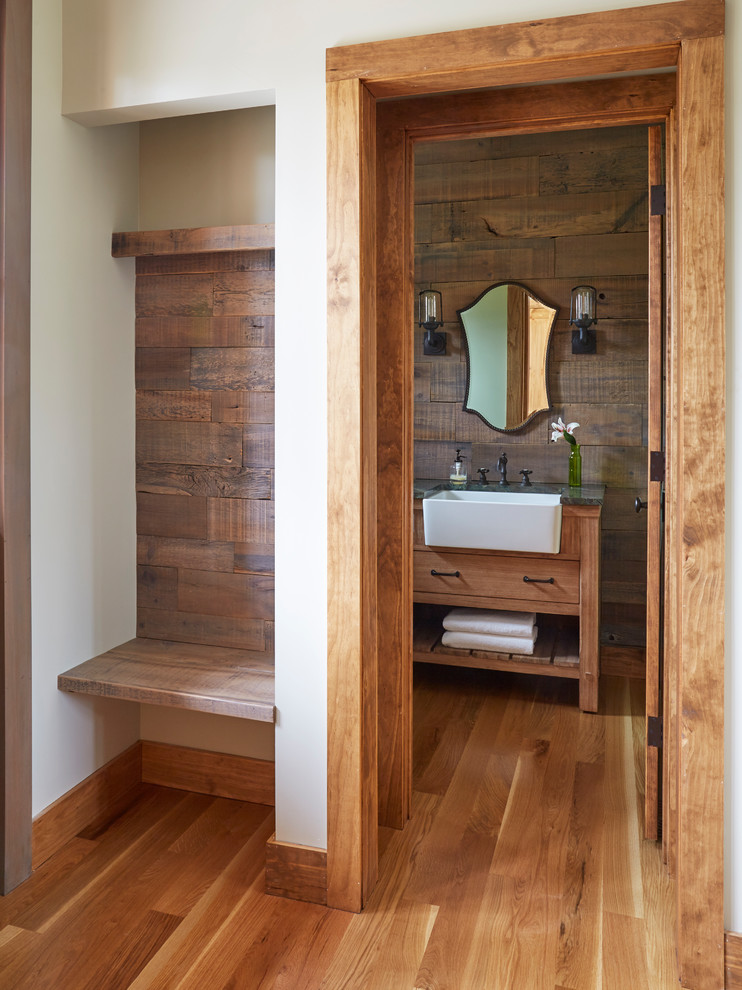 This is an example of a mid-sized country powder room in Chicago with furniture-like cabinets, light wood cabinets, a two-piece toilet, green walls, light hardwood floors, an undermount sink, quartzite benchtops, brown floor, green benchtops, a freestanding vanity and wood walls.
