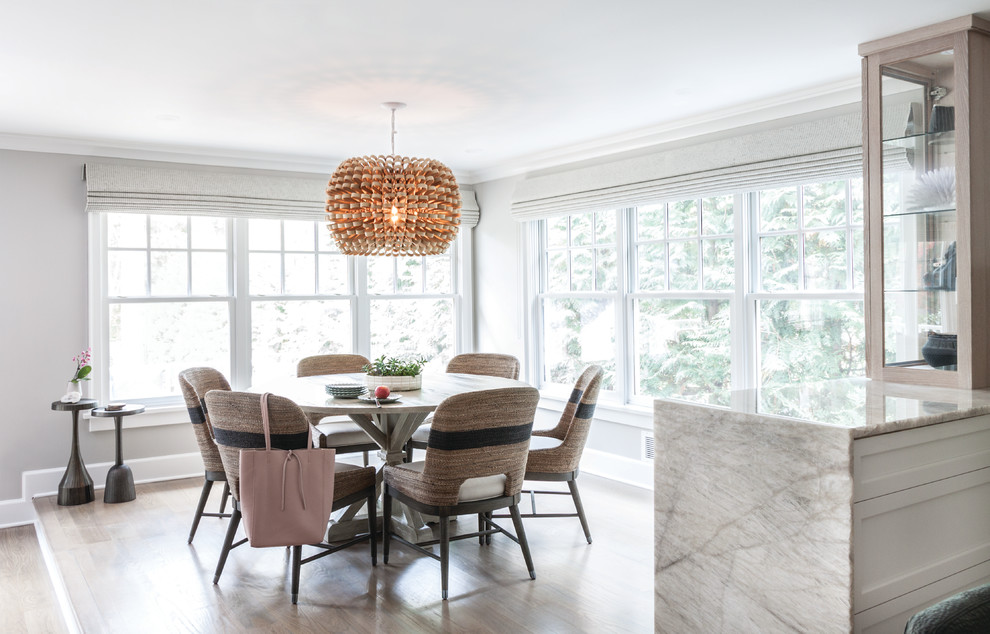 Transitional dining room in New York with beige walls, light hardwood floors and brown floor.