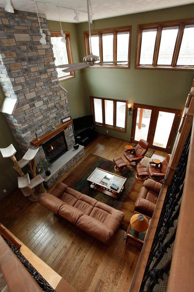 Photo of a mid-sized traditional loft-style living room in Chicago with beige walls, light hardwood floors, a standard fireplace, a stone fireplace surround, a freestanding tv and brown floor.