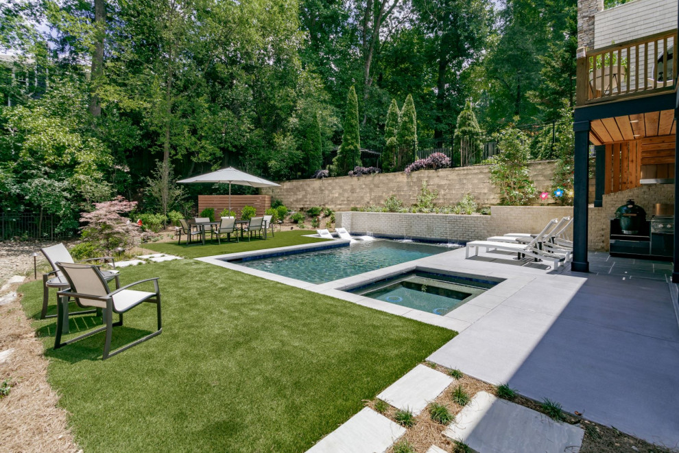 Ispirazione per una piscina minimalista rettangolare di medie dimensioni e dietro casa con una vasca idromassaggio e pavimentazioni in cemento
