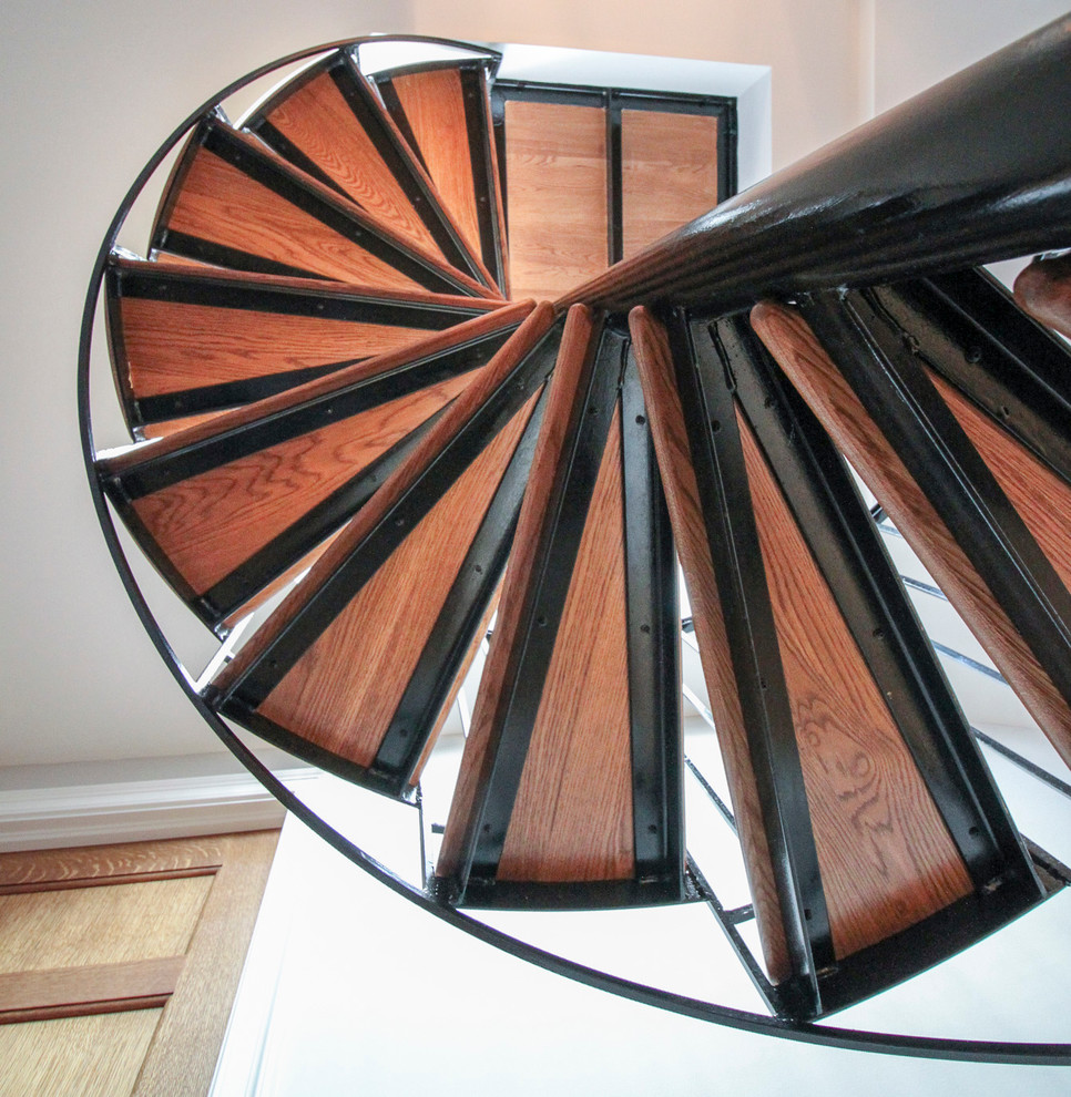 Expansive traditional wood spiral staircase in DC Metro with wood risers and metal railing.