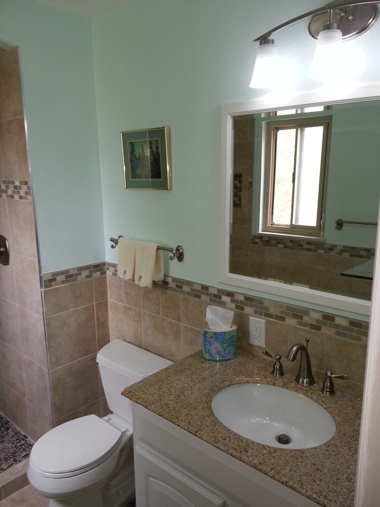 Alcove shower - mid-sized transitional 3/4 beige tile and porcelain tile porcelain tile and beige floor alcove shower idea with raised-panel cabinets, white cabinets, a two-piece toilet, blue walls, an undermount sink, laminate countertops, a hinged shower door and multicolored countertops