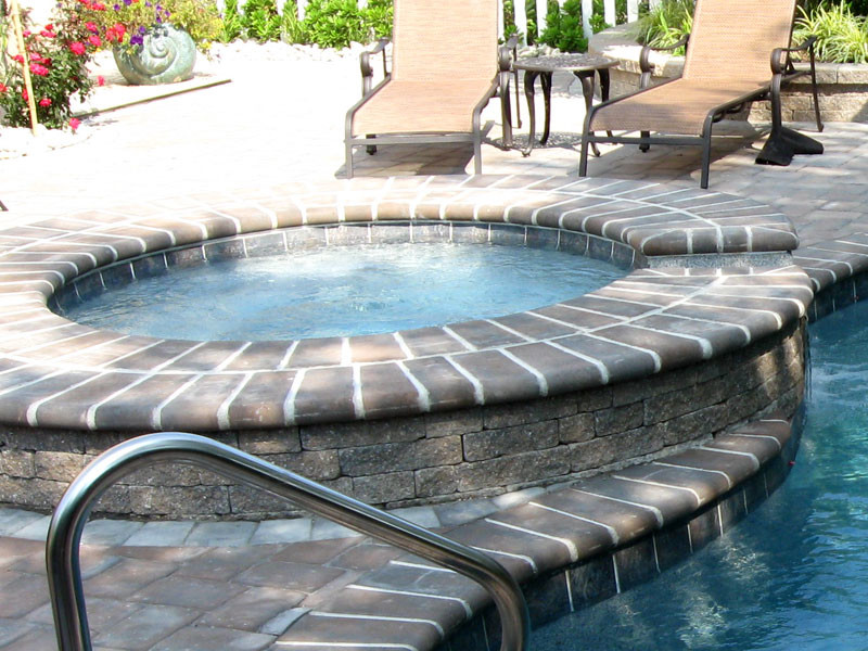 Example of a large transitional backyard concrete paver and round hot tub design in Chicago