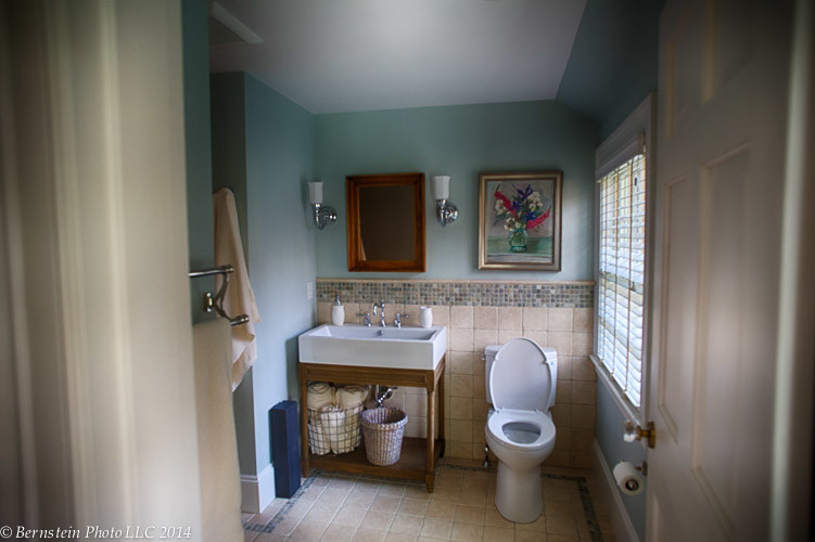 Small traditional kids bathroom in Boston with a pedestal sink, open cabinets, medium wood cabinets, a drop-in tub, a shower/bathtub combo, a two-piece toilet, beige tile, stone tile, blue walls and marble floors.