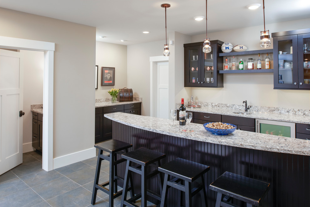Photo of a mid-sized country galley seated home bar in Detroit with an undermount sink, shaker cabinets, black cabinets, quartz benchtops, grey splashback, slate floors, multi-coloured floor and grey benchtop.