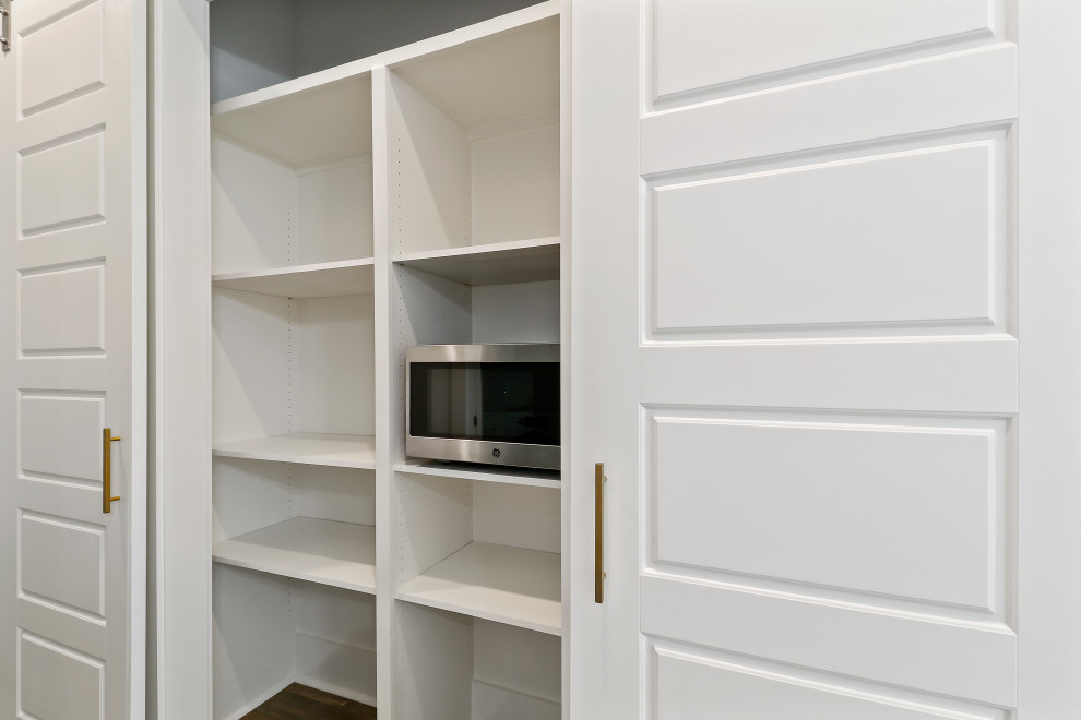 Imagen de armario costero de tamaño medio con puertas de armario blancas, suelo de madera en tonos medios y suelo gris