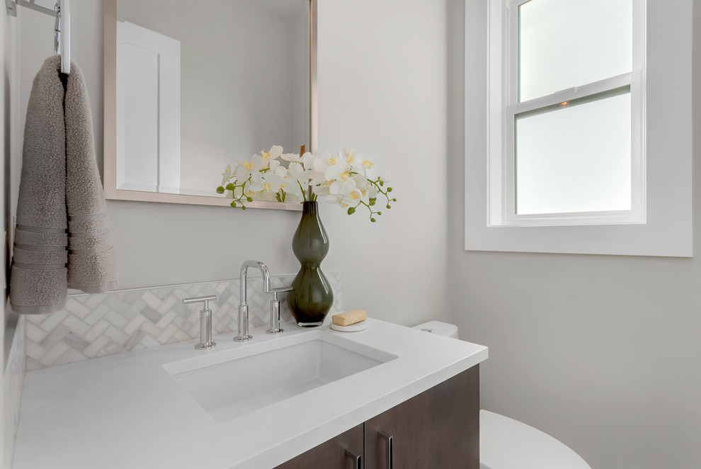 Inspiration for a mid-sized contemporary powder room in Seattle with flat-panel cabinets, dark wood cabinets, a two-piece toilet, gray tile, grey walls, an undermount sink and engineered quartz benchtops.