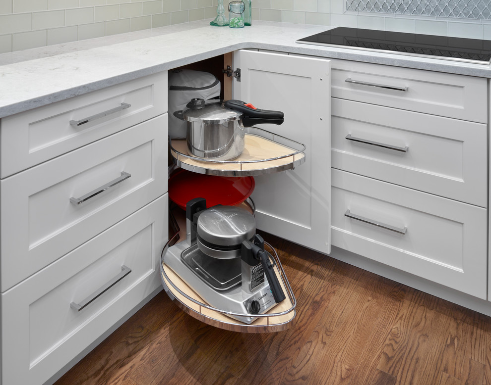 Eat-in kitchen - mid-sized transitional l-shaped medium tone wood floor and brown floor eat-in kitchen idea in Edmonton with a farmhouse sink, recessed-panel cabinets, white cabinets, quartz countertops, gray backsplash, glass tile backsplash, stainless steel appliances and no island