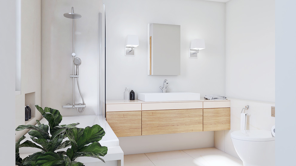 Photo of a mid-sized beach style master bathroom in Cambridgeshire with flat-panel cabinets, light wood cabinets, a drop-in tub, a shower/bathtub combo, a wall-mount toilet, beige tile, ceramic tile, white walls, ceramic floors, an integrated sink, tile benchtops and beige floor.