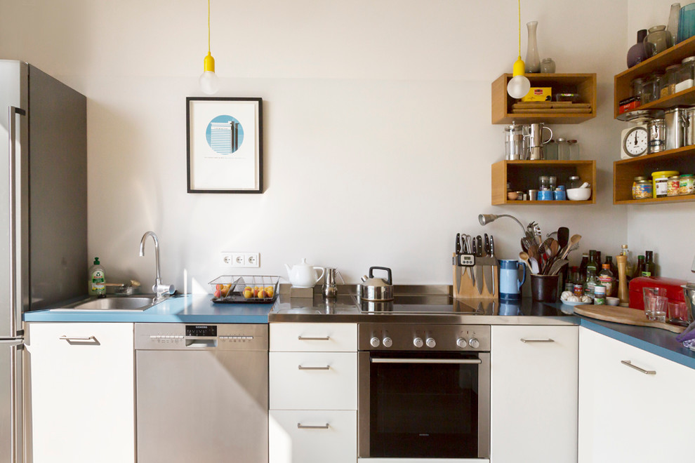 Inspiration for a mid-sized industrial l-shaped kitchen in Berlin with a drop-in sink, flat-panel cabinets, white cabinets, white splashback and stainless steel appliances.