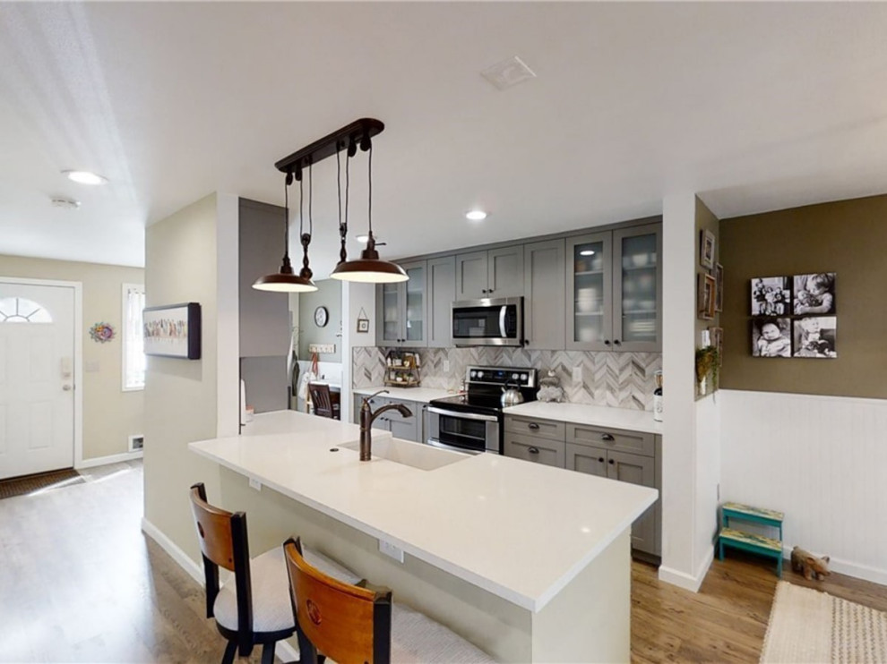 Mid-sized modern galley eat-in kitchen in Seattle with an undermount sink, shaker cabinets, grey cabinets, tile benchtops, multi-coloured splashback, mosaic tile splashback, stainless steel appliances, vinyl floors, with island, brown floor, white benchtop and timber.