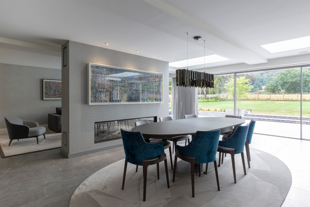 This is an example of a large transitional open plan dining in Cheshire with porcelain floors, grey floor, grey walls and a ribbon fireplace.