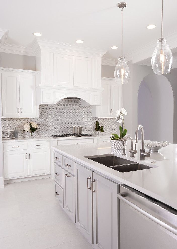 Design ideas for an expansive traditional l-shaped open plan kitchen in Atlanta with an undermount sink, raised-panel cabinets, white cabinets, solid surface benchtops, grey splashback, marble splashback, stainless steel appliances, with island, white floor and white benchtop.