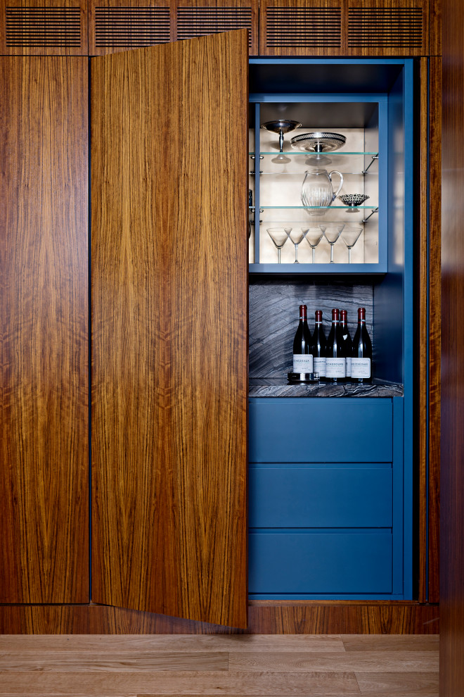 Mid-sized contemporary single-wall home bar in Toronto with flat-panel cabinets, blue cabinets, granite benchtops, multi-coloured splashback, granite splashback, medium hardwood floors, brown floor and multi-coloured benchtop.