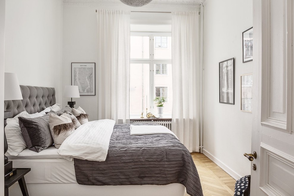 Photo of a scandinavian guest bedroom in Gothenburg with white walls, light hardwood floors and beige floor.