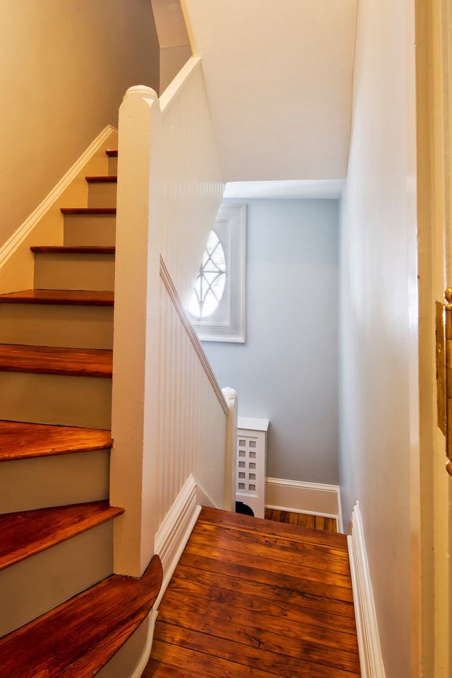 Traditional wood u-shaped staircase in New York with painted wood risers.
