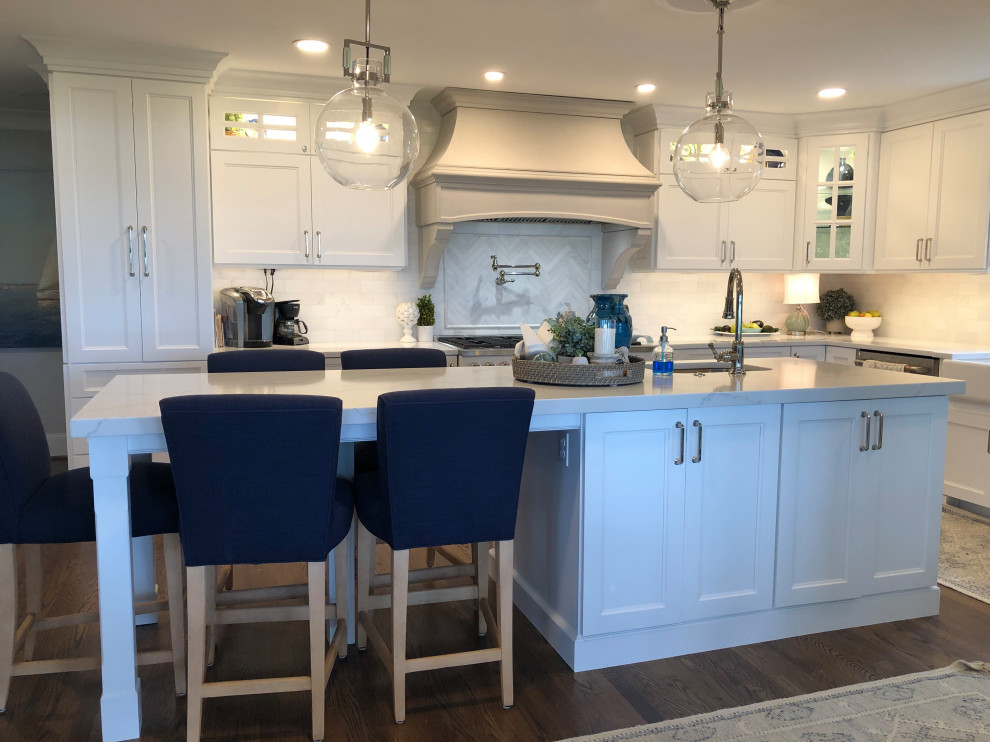 Large transitional l-shaped medium tone wood floor and brown floor eat-in kitchen photo in Baltimore with a farmhouse sink, shaker cabinets, white cabinets, quartz countertops, white backsplash, subway tile backsplash, stainless steel appliances, an island and white countertops