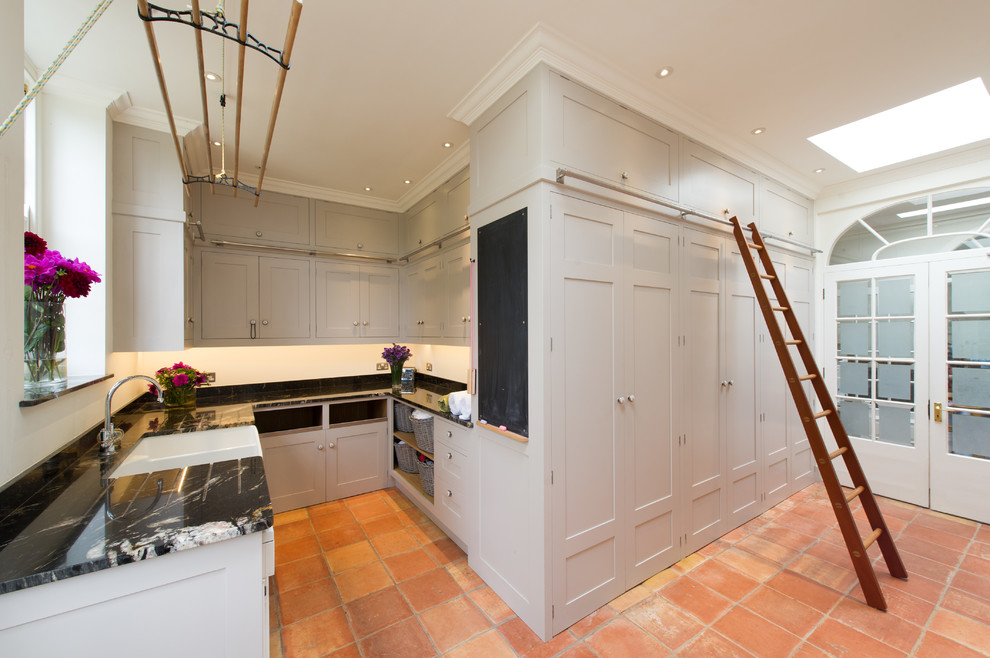 This is an example of a traditional laundry room in Hampshire with terra-cotta floors.