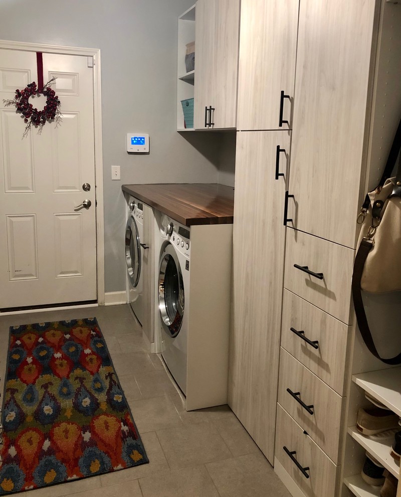 Inspiration for a mid-sized transitional galley utility room in Chicago with an utility sink, flat-panel cabinets, light wood cabinets, grey walls, porcelain floors, a side-by-side washer and dryer, grey floor and brown benchtop.