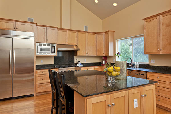 Mid-sized transitional l-shaped medium tone wood floor open concept kitchen photo with a double-bowl sink, shaker cabinets, medium tone wood cabinets, granite countertops, black backsplash, stainless steel appliances, beige walls and an island