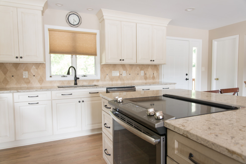 Kitchen - transitional l-shaped light wood floor kitchen idea with an undermount sink, raised-panel cabinets, white cabinets, beige backsplash, stainless steel appliances, an island and beige countertops