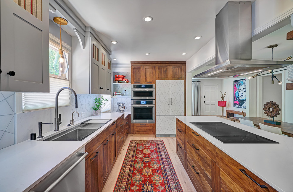 This is an example of a mid-sized contemporary l-shaped eat-in kitchen in Sacramento with an undermount sink, shaker cabinets, medium wood cabinets, quartz benchtops, white splashback, porcelain splashback, stainless steel appliances, light hardwood floors, a peninsula, multi-coloured floor and white benchtop.