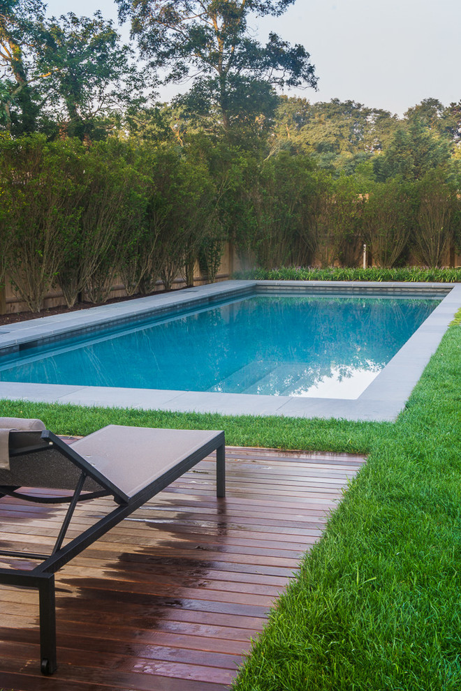 This is an example of a mid-sized modern backyard rectangular pool in Boston with a pool house and decking.