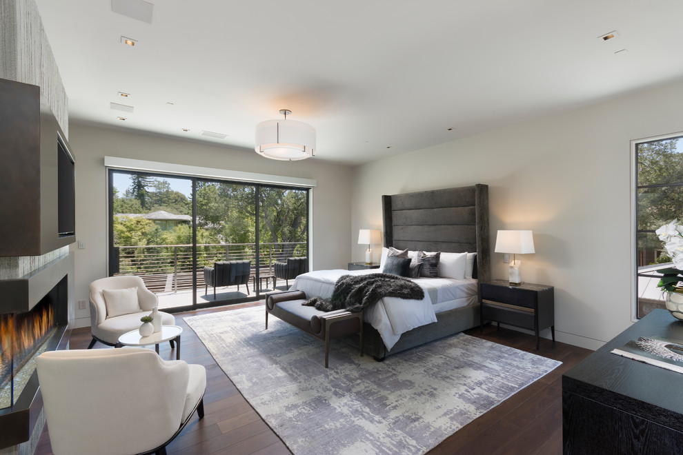 Design ideas for a contemporary bedroom in Orange County with white walls, dark hardwood floors, a ribbon fireplace and brown floor.