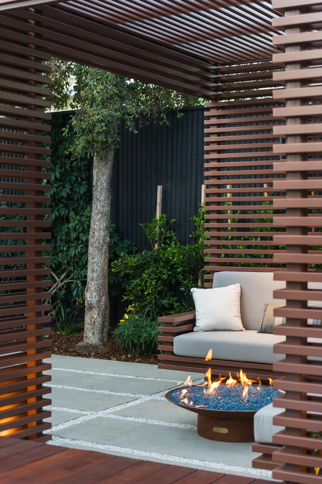 This is an example of a small contemporary backyard deck in Los Angeles with a fire feature and a pergola.