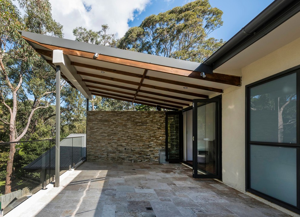 Design ideas for a mid-sized modern verandah in Melbourne with natural stone pavers and a roof extension.