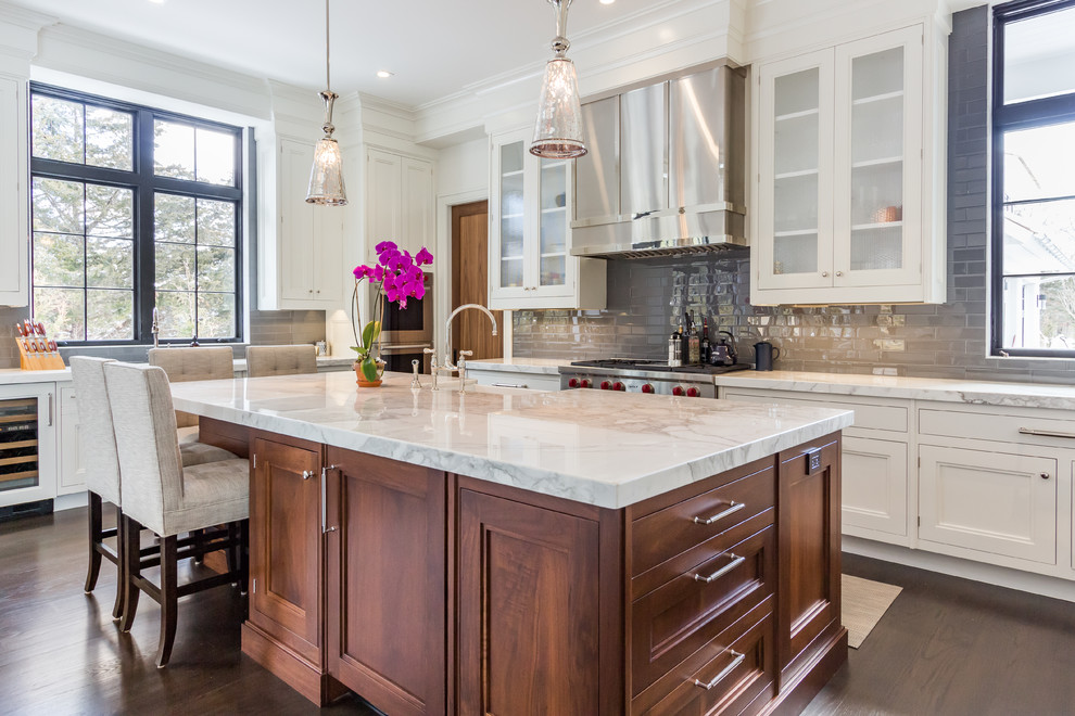 Inspiration for a large transitional u-shaped kitchen in Other with a farmhouse sink, white cabinets, marble benchtops, grey splashback, subway tile splashback, stainless steel appliances, dark hardwood floors, with island and recessed-panel cabinets.