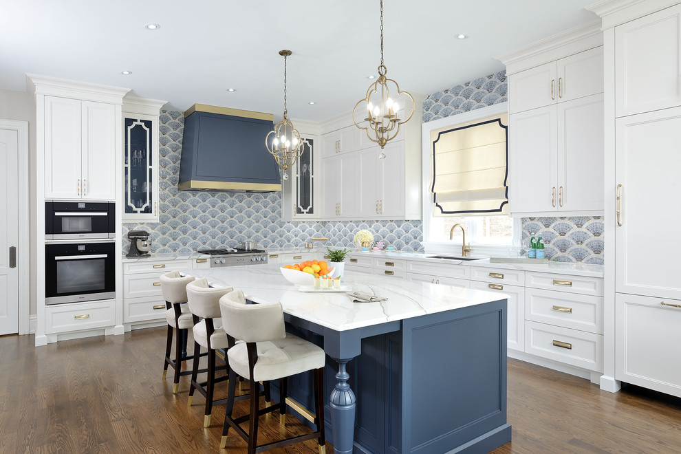 Inspiration for a large traditional l-shaped eat-in kitchen in Toronto with an undermount sink, recessed-panel cabinets, white cabinets, quartz benchtops, blue splashback, mosaic tile splashback, stainless steel appliances, medium hardwood floors, with island, brown floor and white benchtop.