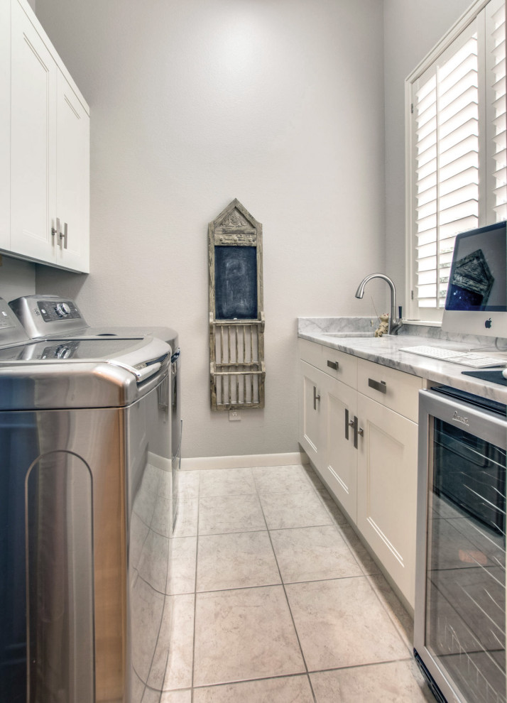 This is an example of a small modern galley dedicated laundry room with a single-bowl sink, shaker cabinets, white cabinets, marble benchtops, grey walls, porcelain floors, a side-by-side washer and dryer, white floor and white benchtop.
