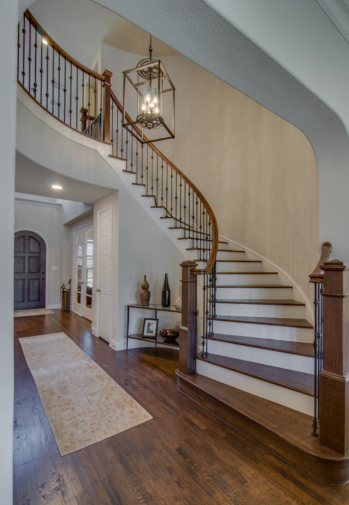 This is an example of an expansive transitional wood curved staircase in Dallas with painted wood risers and mixed railing.