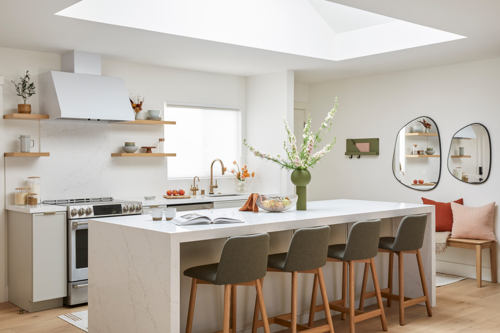 Idéer för små minimalistiska vitt kök med öppen planlösning, med en undermonterad diskho, skåp i shakerstil, grå skåp, bänkskiva i kvarts, vitt stänkskydd, rostfria vitvaror, ljust trägolv, en köksö och brunt golv